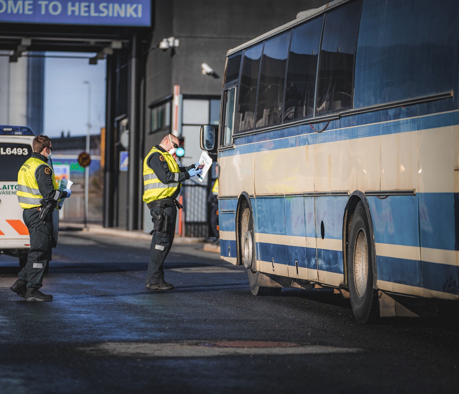 Rajavartijat tarkistavat linja-autonkuljettajan asiakirjoja satamassa.