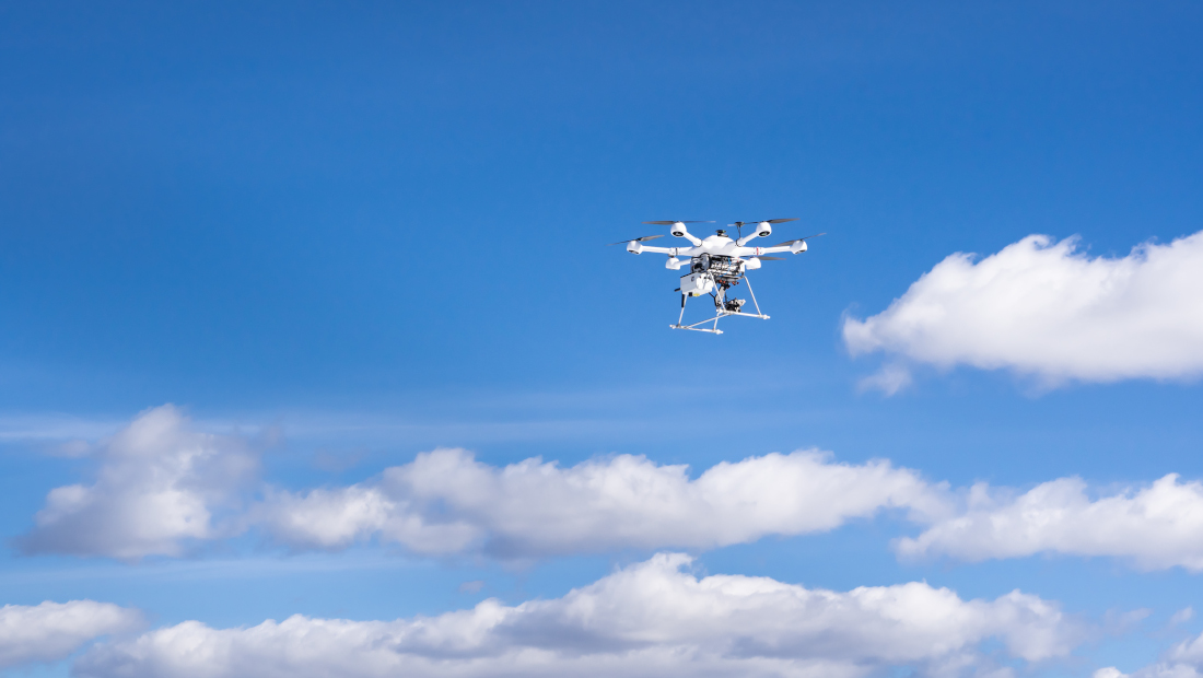 Drone lentää kirkkaalla taivaalla.