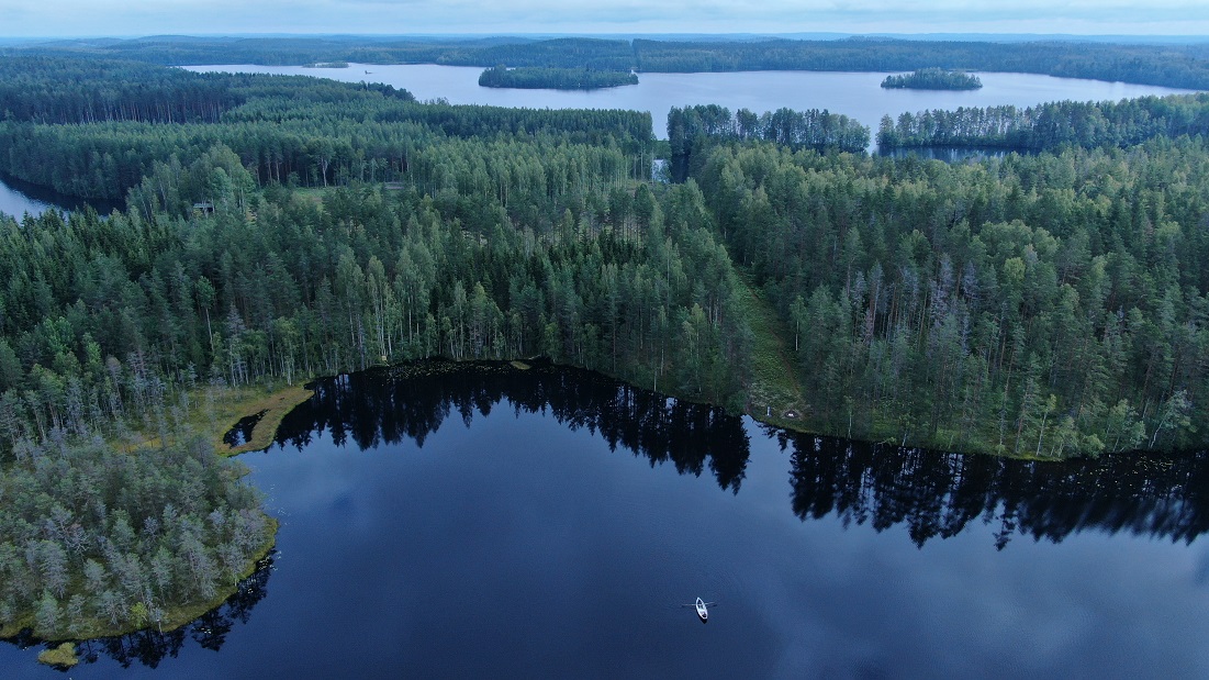 Ilmakuva maastorajasta, vihreää metsää ja vesistöä.