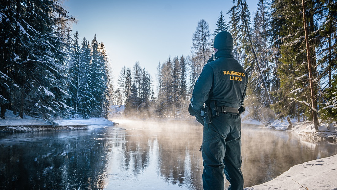 Rajavartija katsoo joelle lumisessa maisemassa.