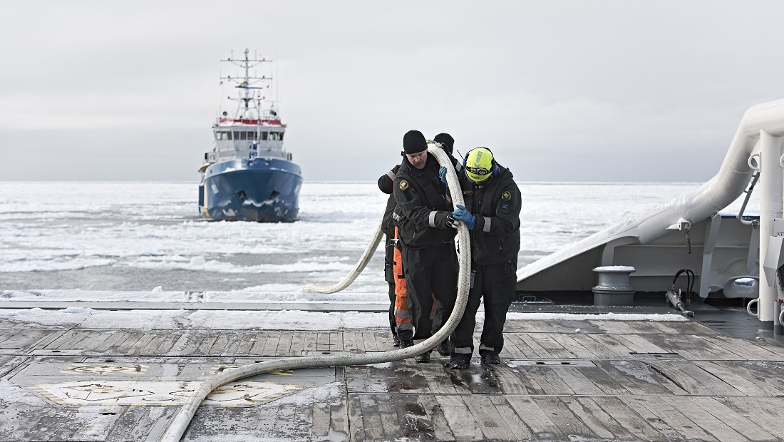 Merivartijat ja pelastajat nostavat puomia laivaan, takana toinen laiva.