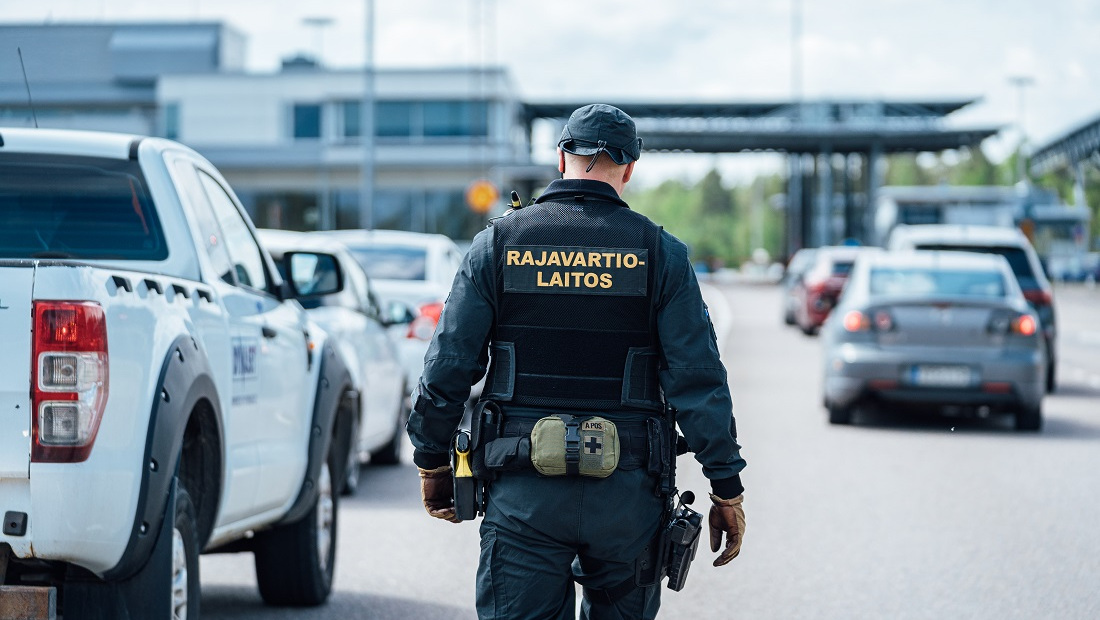 Rajavartija kävelee autojonojen välissä kohti rajanylityspaikkaa.