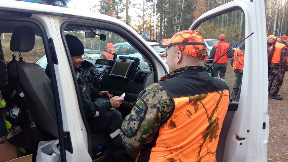 Rajavartija ja metsästäjä keskustelevat partioauton ovella.