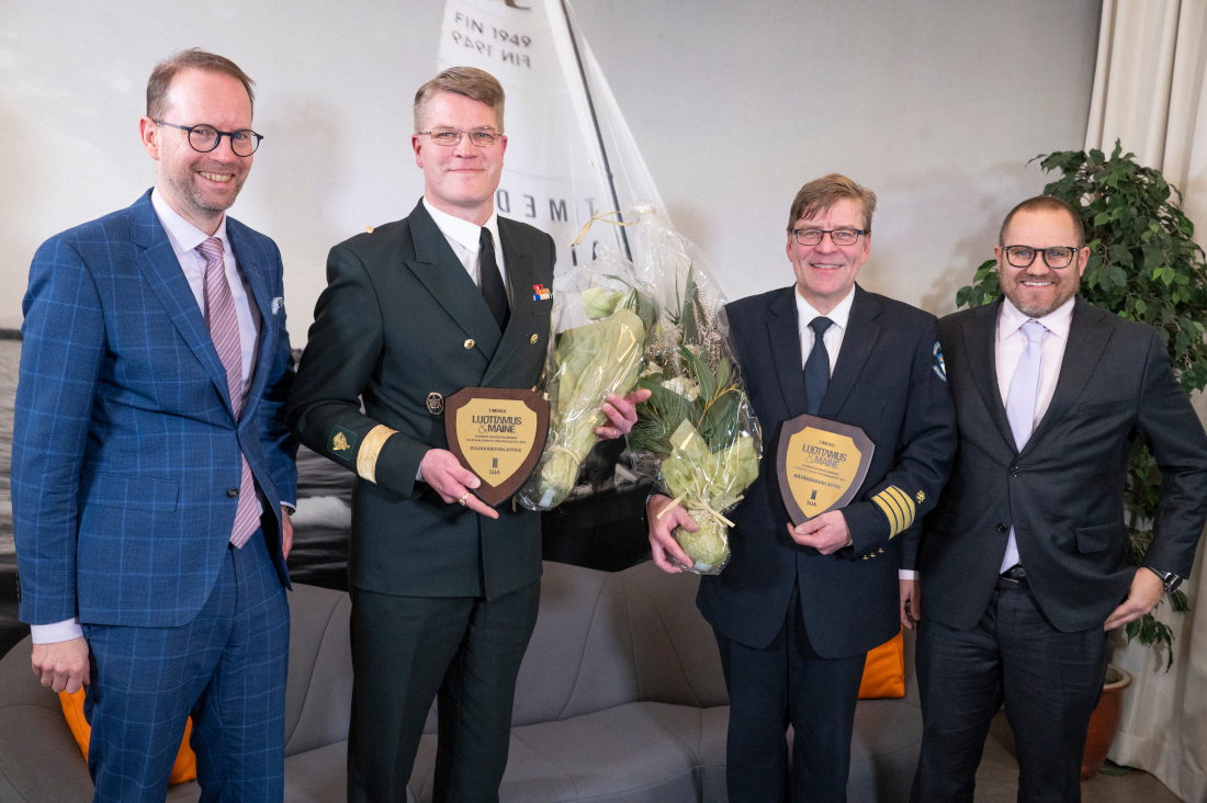 Hanén kukkakimppu ja palkintokilpi kädessä, vierellä kolme muuta henkilöä.