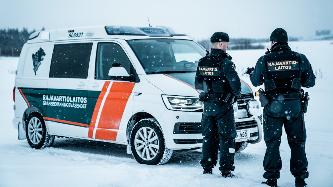 Kaksi rajavartijaa ja partioauto lumisella lentokentällä.