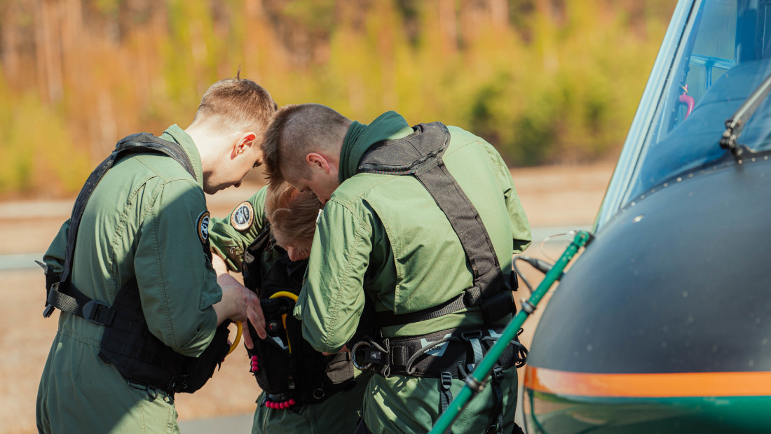 Kolme lentäjää tutkii jotakin ryhmässä päät kumartuneina yhteen.