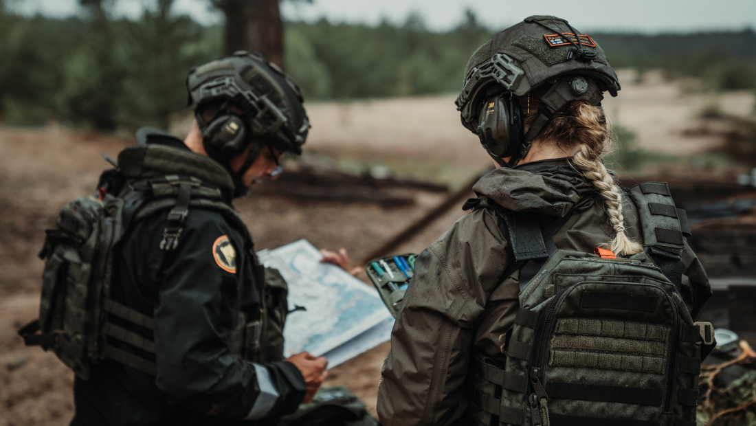 Kaksi sotilasasuista henkilöä katsoo karttaa.