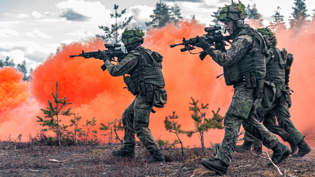 Special border jaegers train in the terrain, with red smoke behind them.
