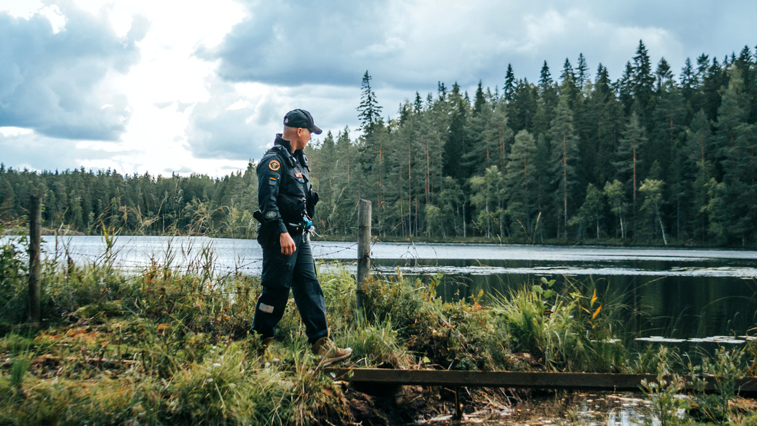 Rajavartija partioi maastossa. Taustalla järvi ja metsää.
