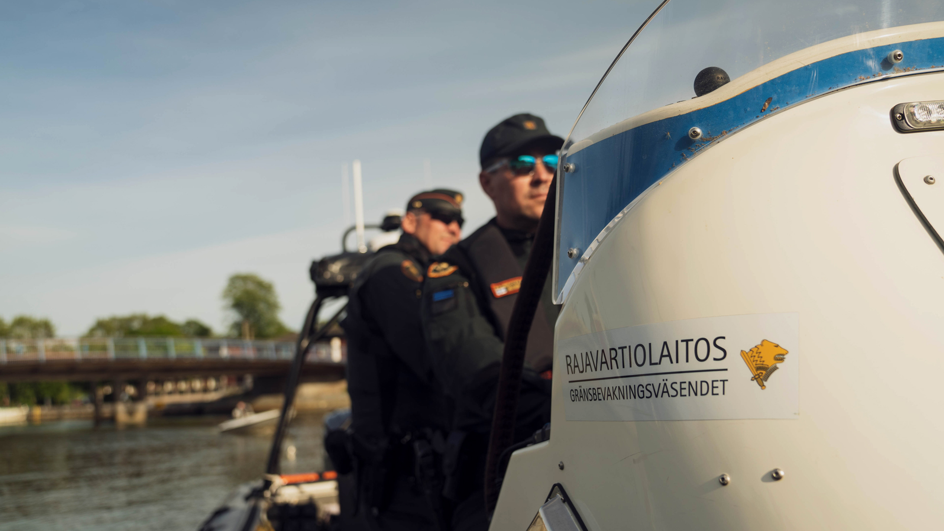 Kaksi rajavartijaa ajavat partioveneessä Susisaaressa saaristomaisemassa.