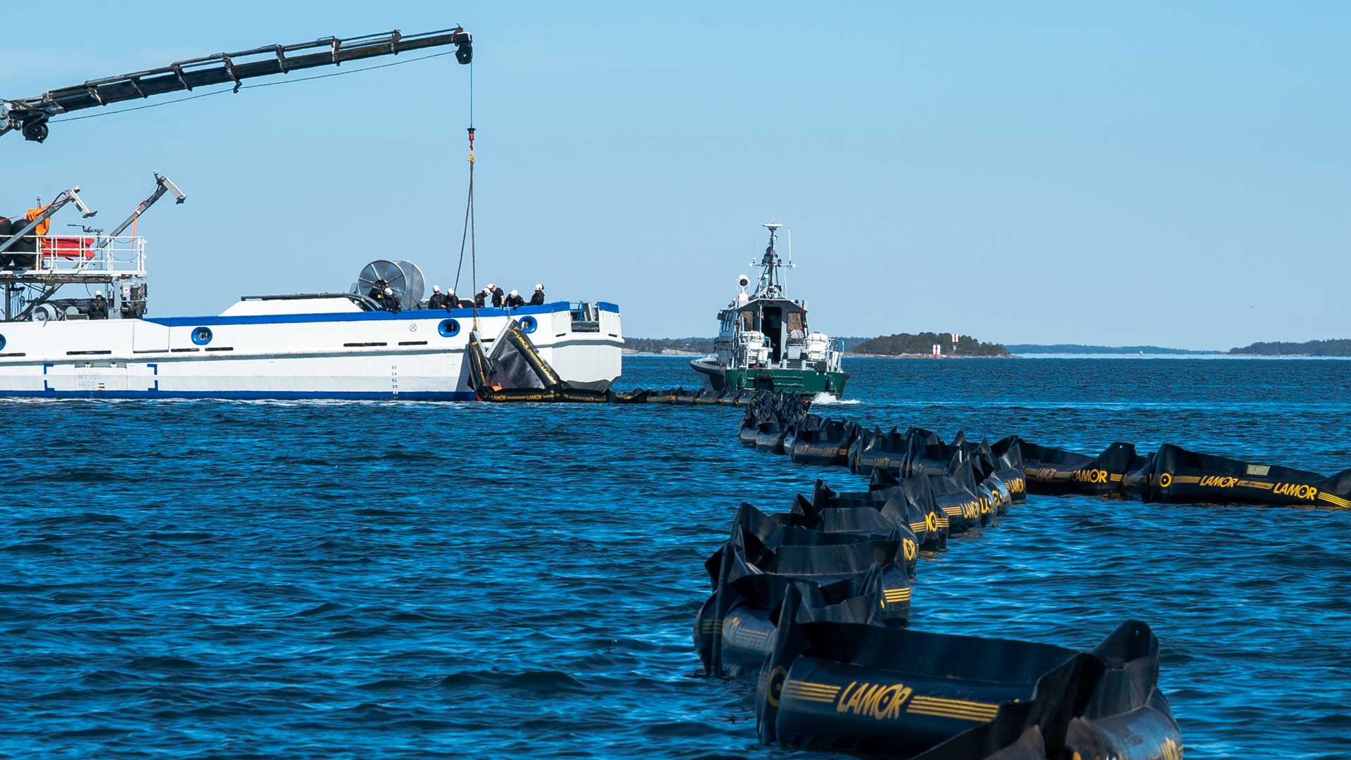 An oil spill response exercise, with a patrol vessel and an oil boom at sea.