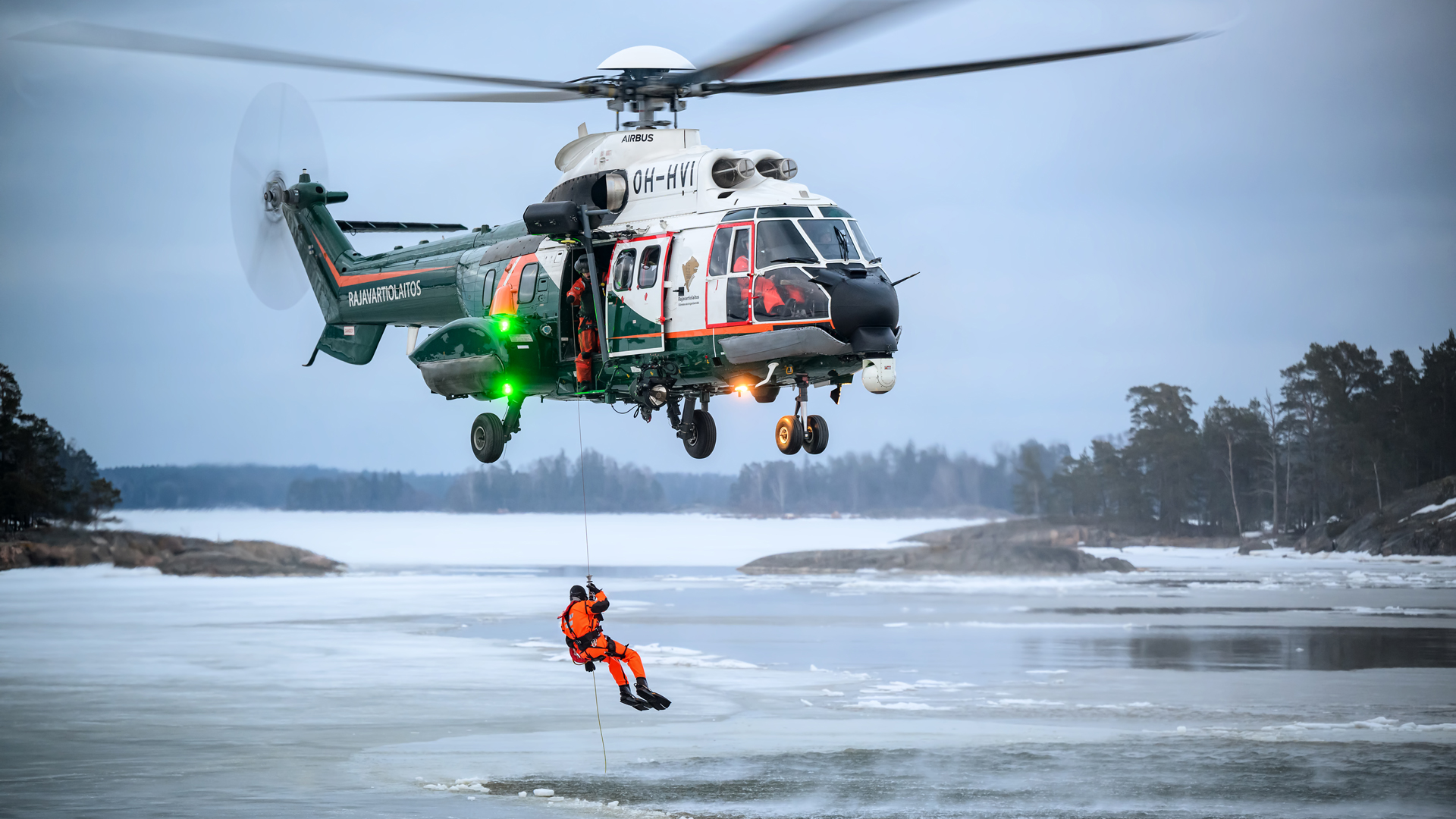A rescue swimmer descending from a helicopter down to a wintry sea. Photo: Lloyd Horgan
