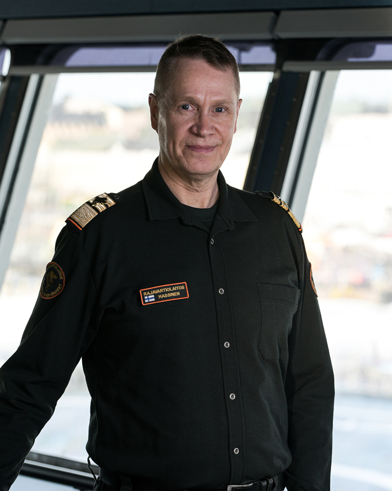 Gränsbevakningschef Markku Hassinen står på bryggan på ett bevakningsfartyg och tittar in i kameran.