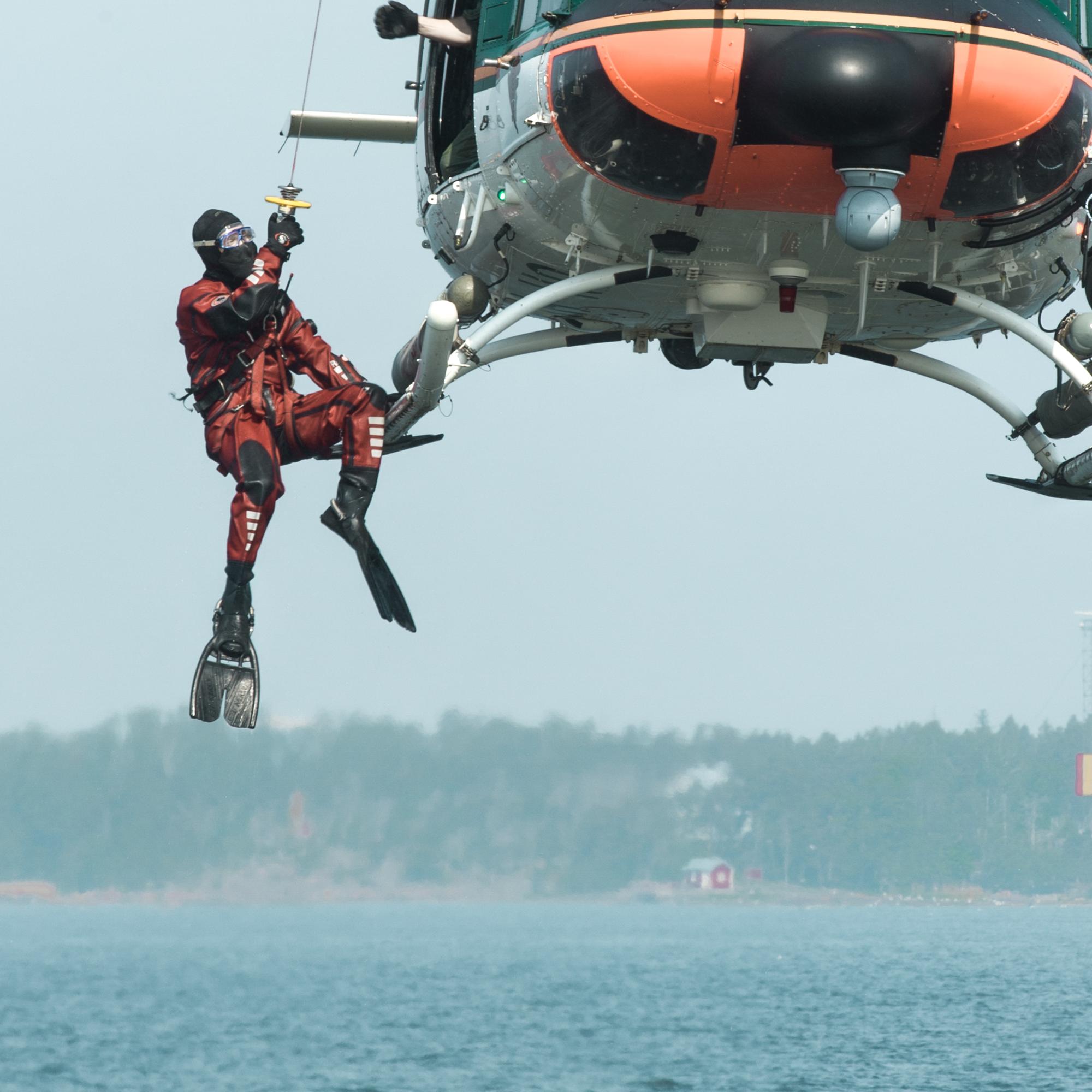 Pintapelastaja laskeutuu helikopterista kohti merta.