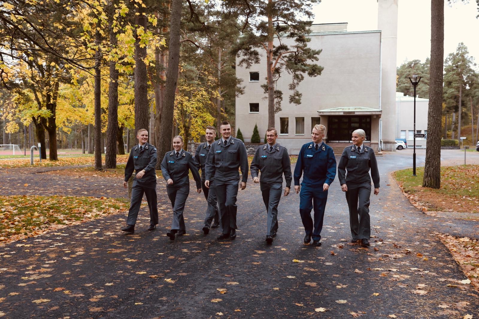 Seitsemän kadettia kävelee kuvaajaa kohti maanpuolustuskorkeakoulun edessä.