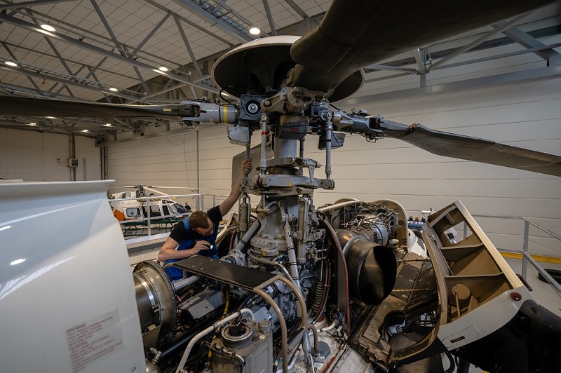 Mekaanikko huoltaa helikopteria hallissa.