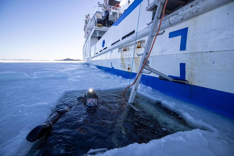 Vartiolaiva väylällä ja sukeltaja avannossa.