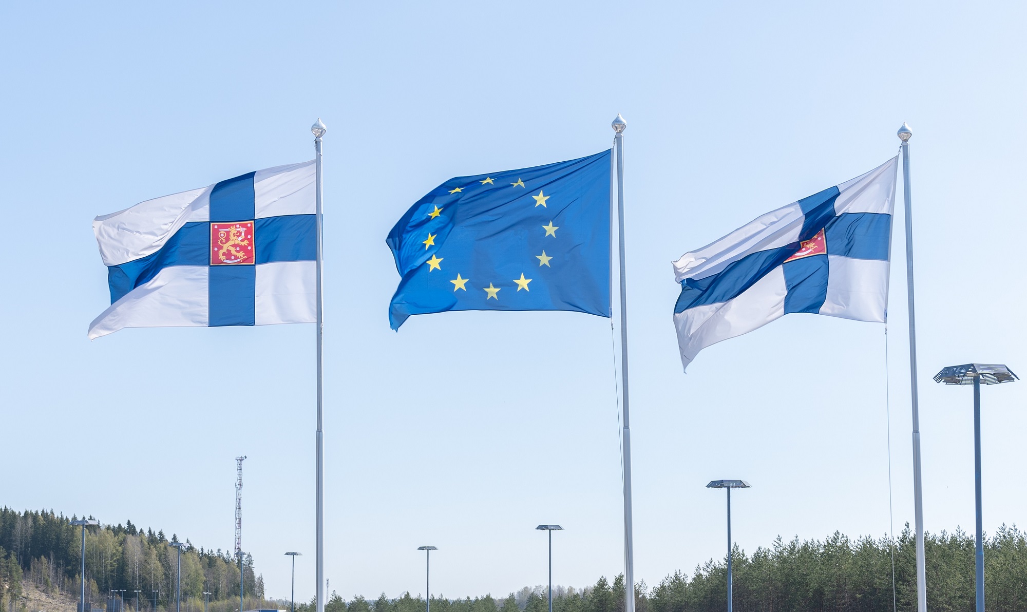 Kaksi Suomen lippua ja Euroopan unionin lippu vierekkäin lipputangoissa.