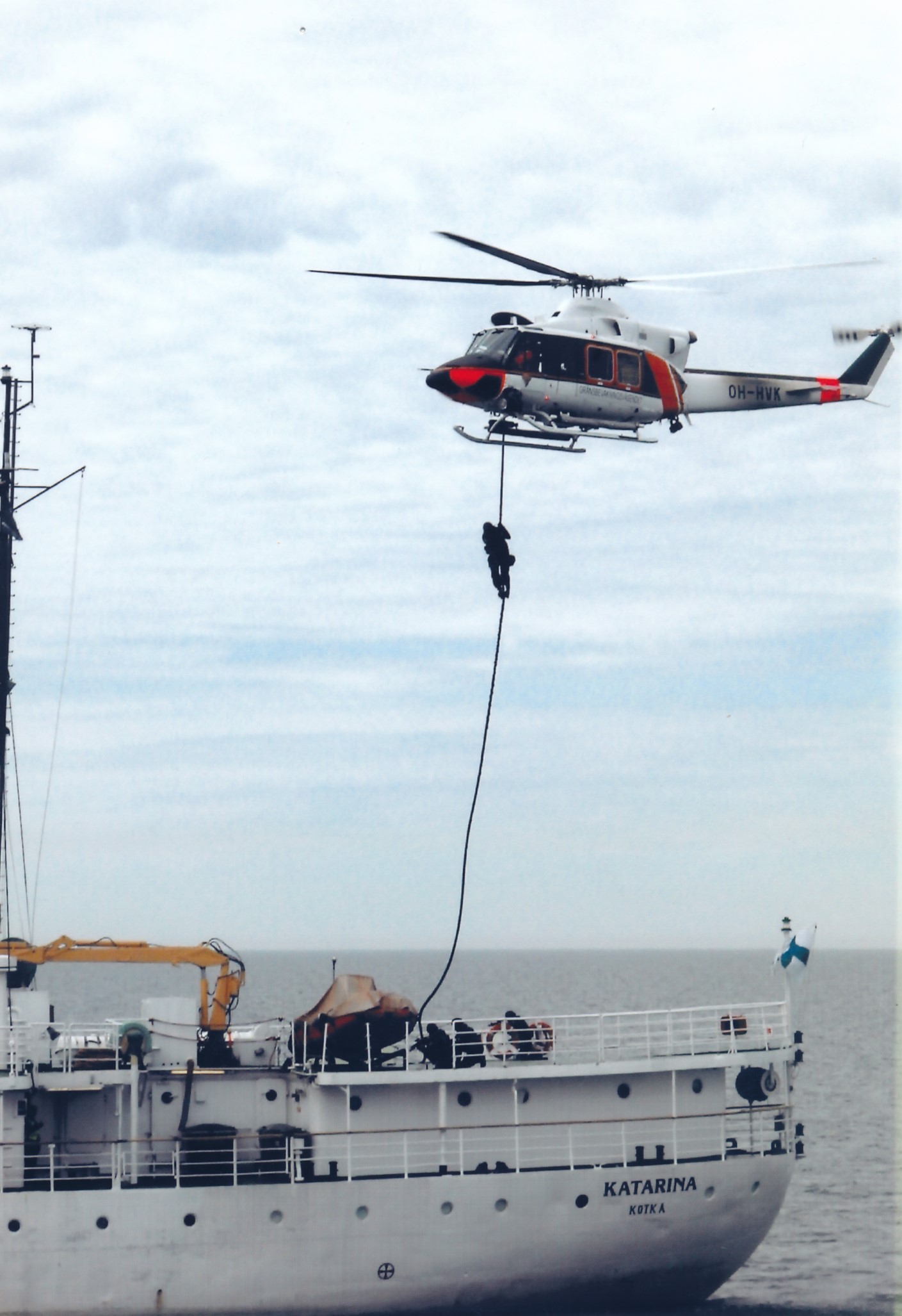 Män från specialtrupper klättrar ner längs ett rep till fartygsdäcket från en helikopter som svävar ovanför.