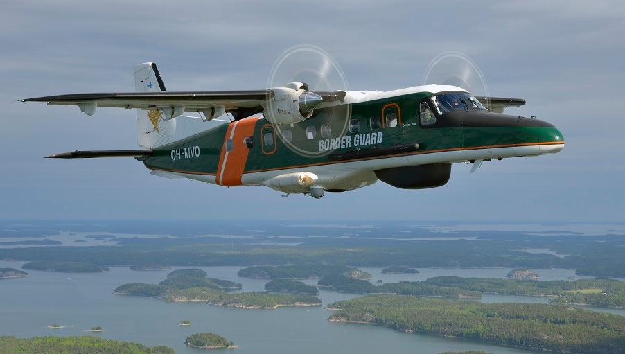 Flygbild från ett flygande tvåmotorigt övervakningsflygplan ovanför ett skärgårdslandskap.