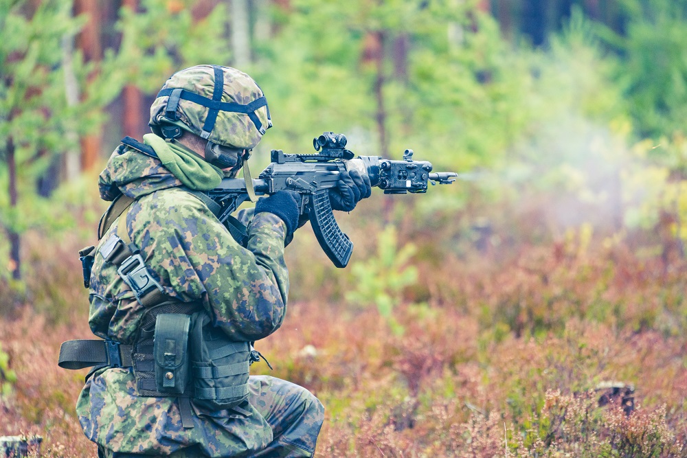 Erikoisrajajääkäri tähtää rynnäkkökiväärillä metsässä.