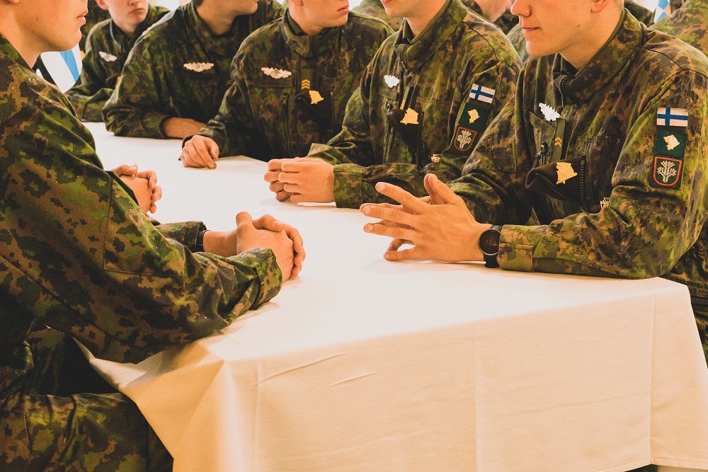 Varusmiehiä istuu pöydän ääressä.