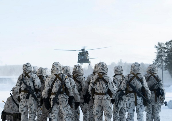 Rajajääkärit katsovat lähestyvää helikopteria lumisessa maisemassa.