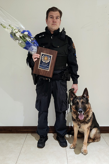 Koiranohjaaja ja Clapton poseeraavat palkintotaulun ja kukkien kanssa.