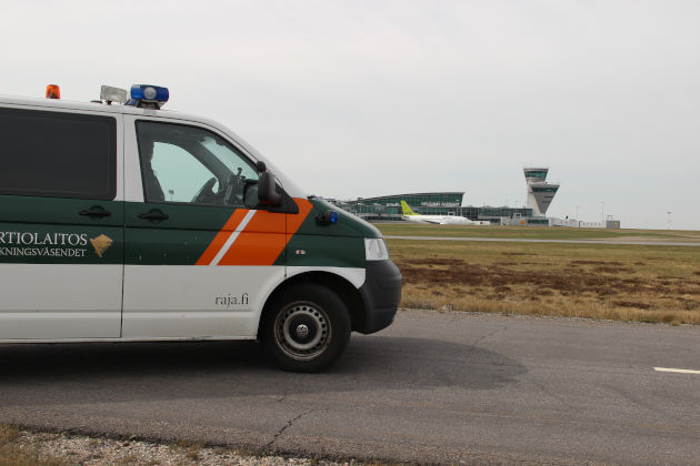 Etualalla Rajavartiolaitoksen partioauto. Taka-alalla lentokone ja Helsinki-Vantaan lentoasema.