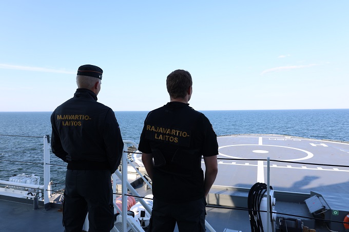 Kaksi merivartijaa turvan kannella selin kohti kameraa.