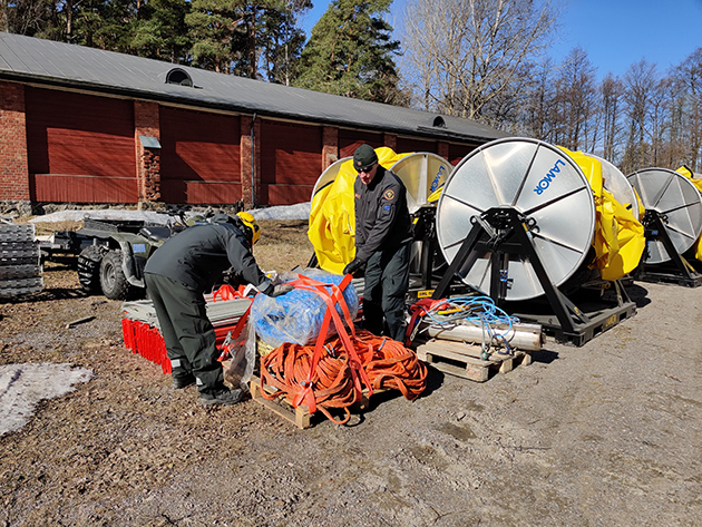 Sjöbevakarna fäster oljebekämpningsmateriel för transporten.