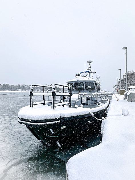En patrullbåt i snöfall vid bryggan.