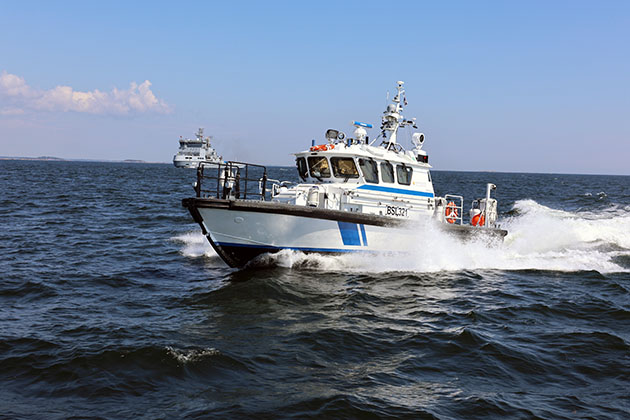 Gränsbevakningens patrullbåt är i farten, i bakgrunden Försvarsmaktens fartyg.