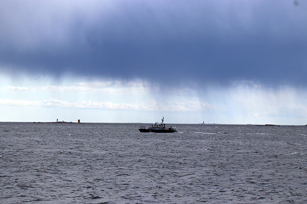 En patrullbåt på havet. Regnmoln närmar sig på himlen.