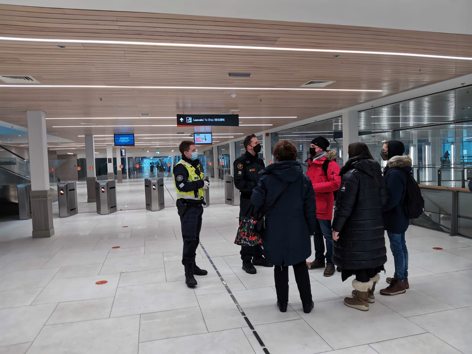 Rajaviranomaiset opastavat matkustajia satamaterminaalissa.