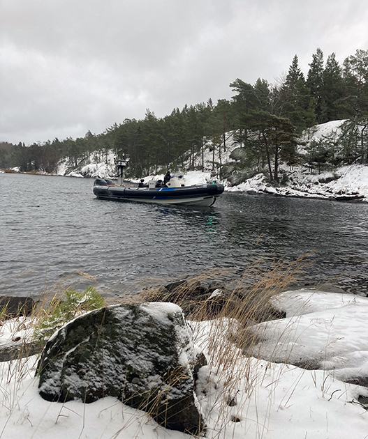 Nopea vene saaristossa. Rannoilla lumipeite.