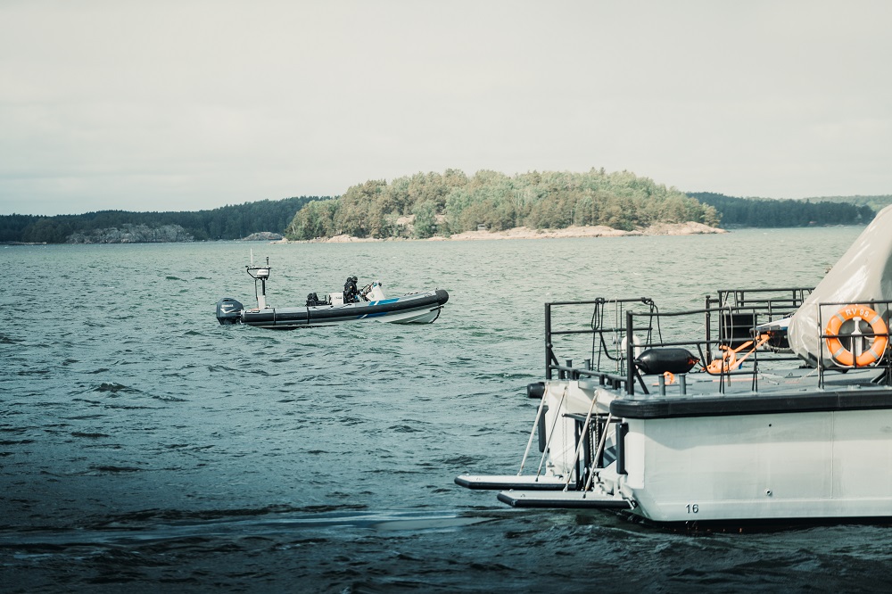 En snabb båt på havet. I förgrunden kustbevakningsbåtens akterdäck.