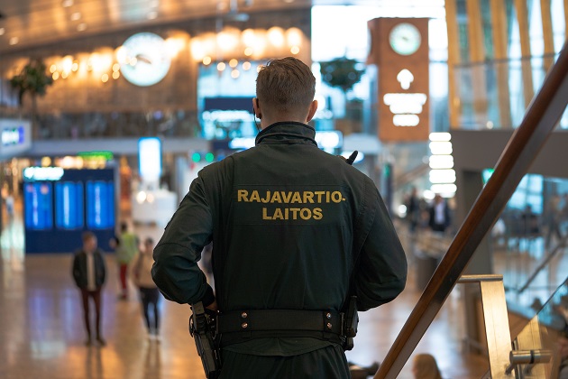 En gränsbevakare med ryggen mot kameran på en flygplats.