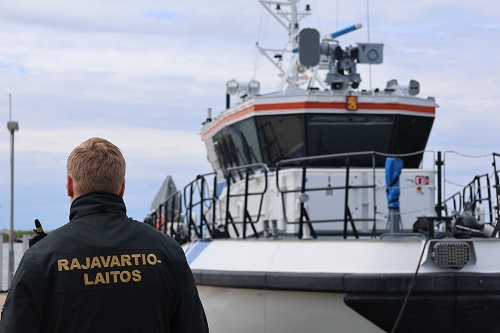 Rajavartiolaitoksen virkamies ja rannikkovartiovene.
