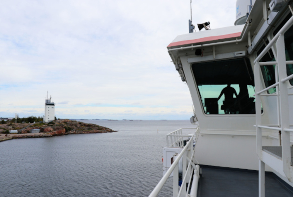 Ett bevakningsfartyg är på väg ut på havet och passerar spetsen av en udde. På kommandobryggan syns befälhavarens silhuett.