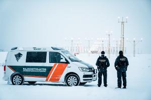 Kaksi rajavartijaa ja partioauto lumisella lentokentällä.