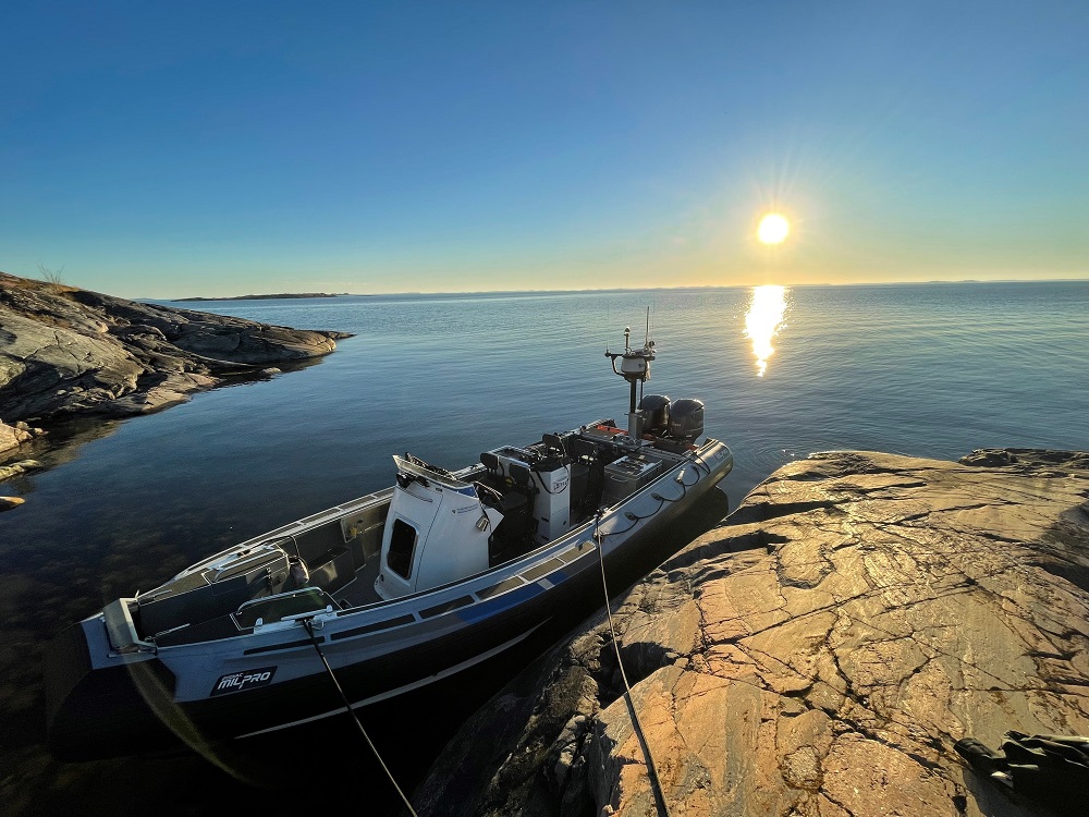 Vene kiinni kalliossa. Aurinko laskee merelle taustalla.