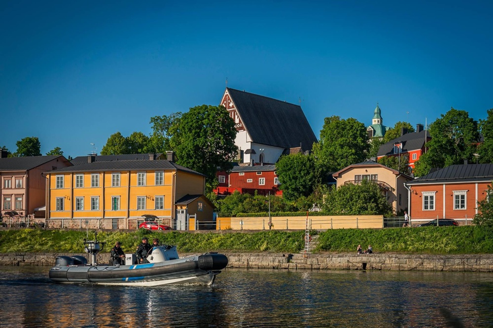 Rajavartiolaitoksen partio nopeaveneellä porvoonjoessa. Taustalla Porvoon vanhan kaupungin värikkäitä puutaloja.