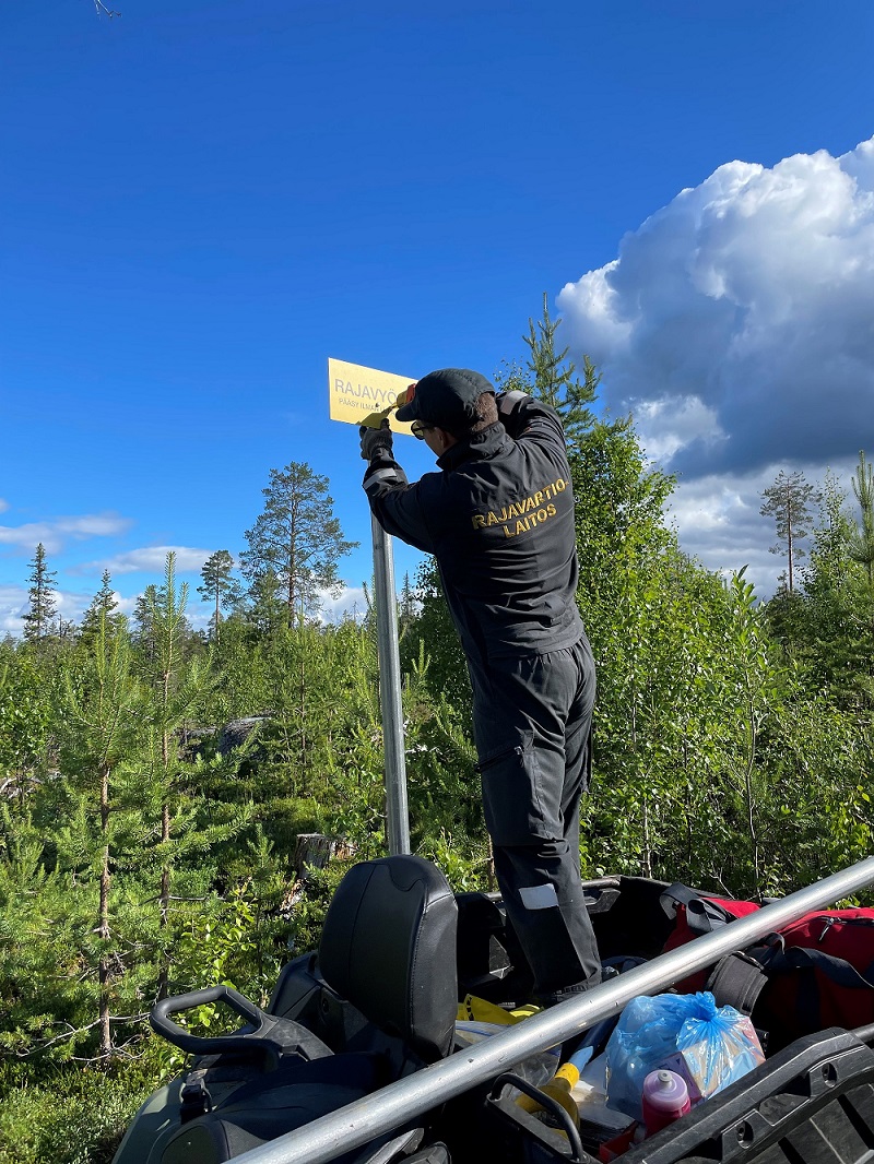 I bilden finns gränsbevakare och gul gränszonstavla.