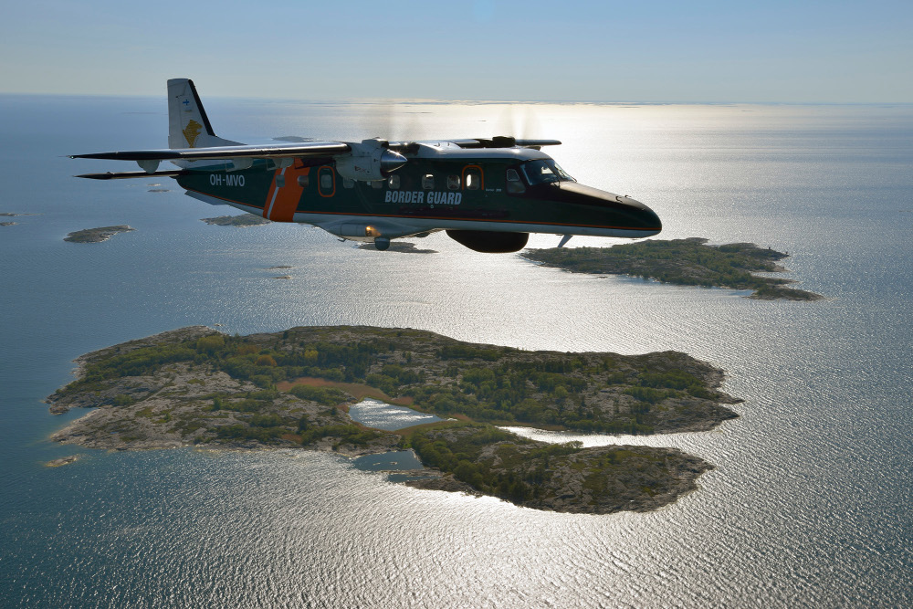 Airplane over archipelago. Calm sea in the background with significant sun reflection.