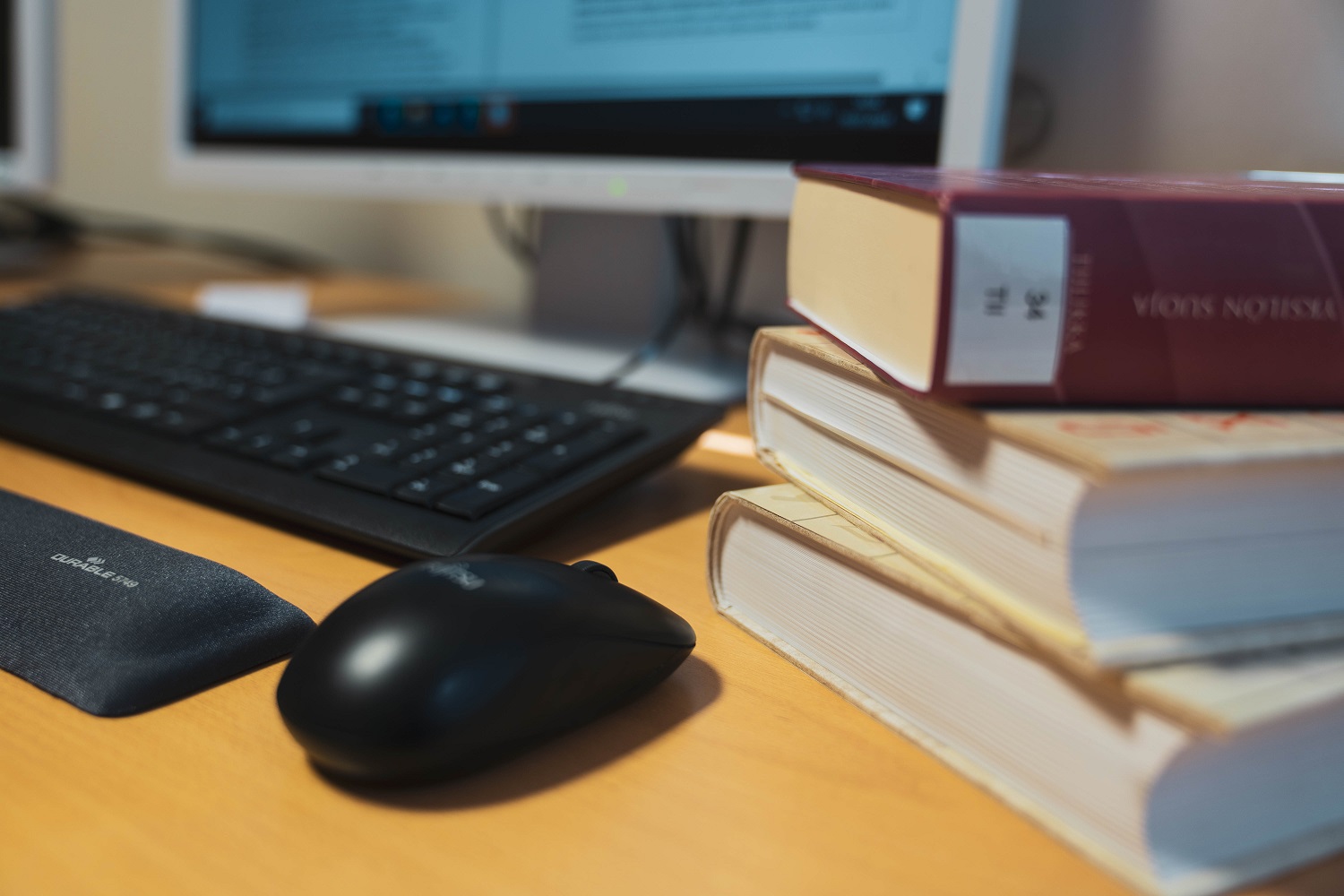 A stack of books and a computer on a desk.