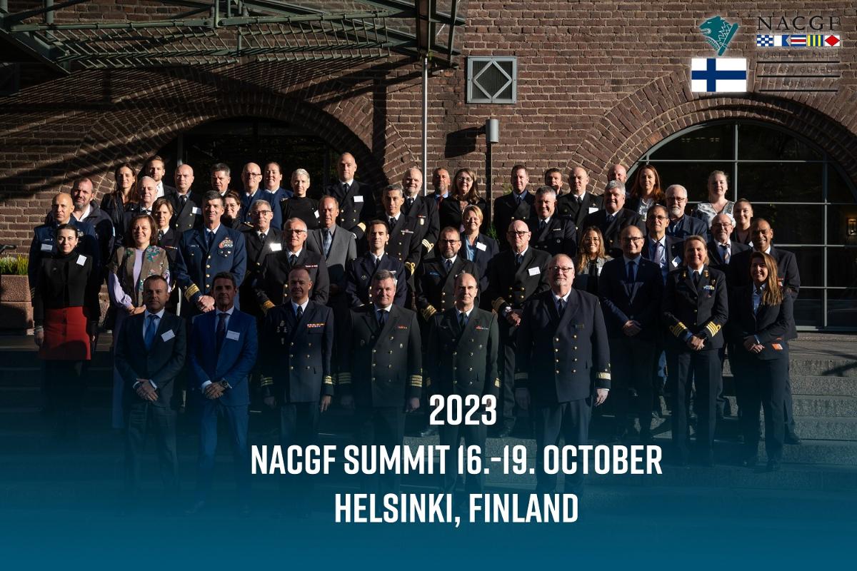 Ryhmäkuva otettu tiiliseinän edessä. Kuvassa uniformuun pukeutuneita ihmisiä ja teksti NACGF SUMMIT 16-19 OCTOBER, HELSINKI, FINLAND.