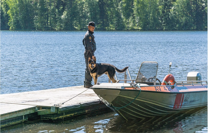 Rajavartija ja rajakoira laiturilla. Vieressä vene.