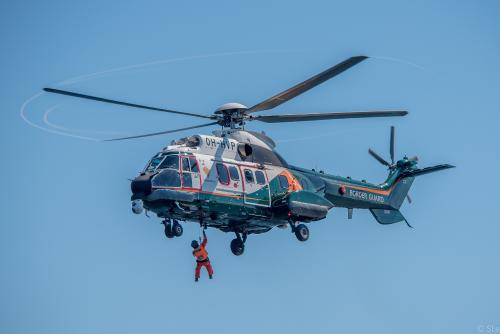 En räddare hänger fast vid räddningshelikopterns vinsch.