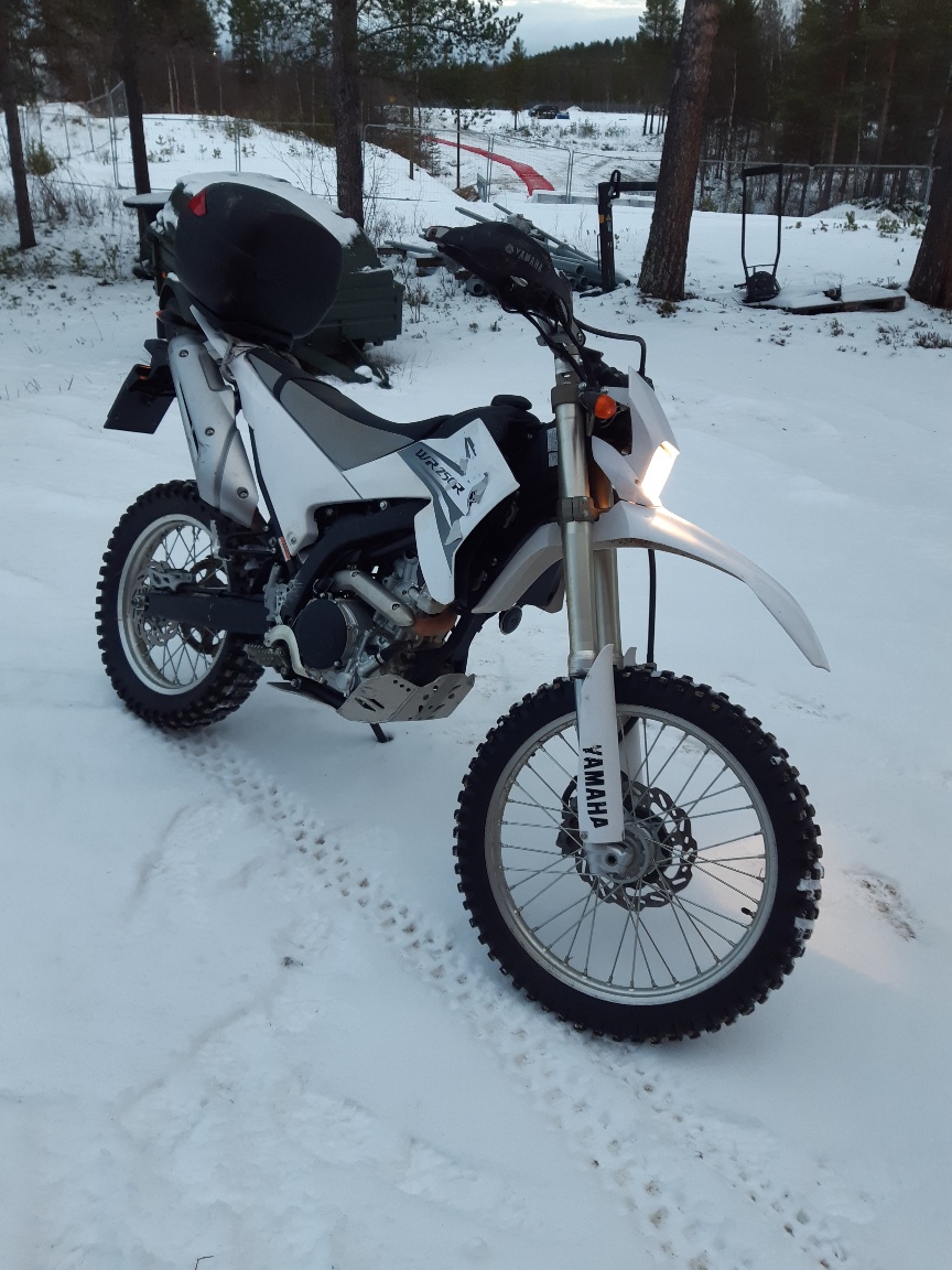 En terrängmotorcykel i ett snöigt landskap.